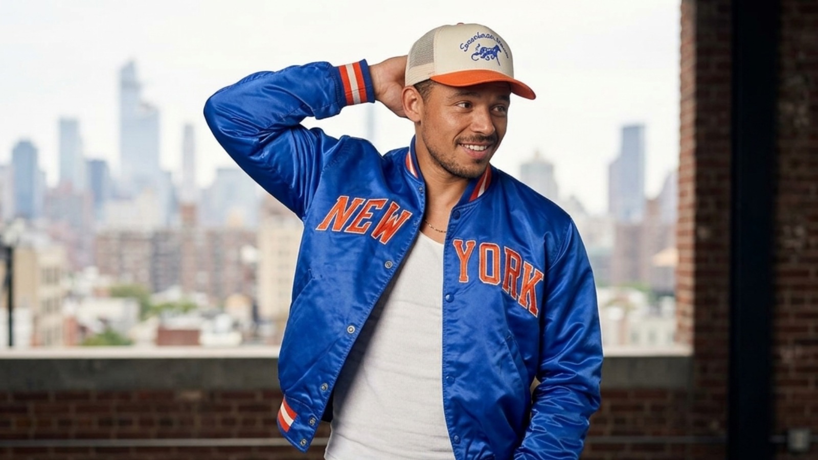 Anthony Ramos blue satin varsity bomber jacket from The Tonight Show 2026 featuring “NEW YORK” appliqué lettering, striped rib-knit trims, and snap-button closure.