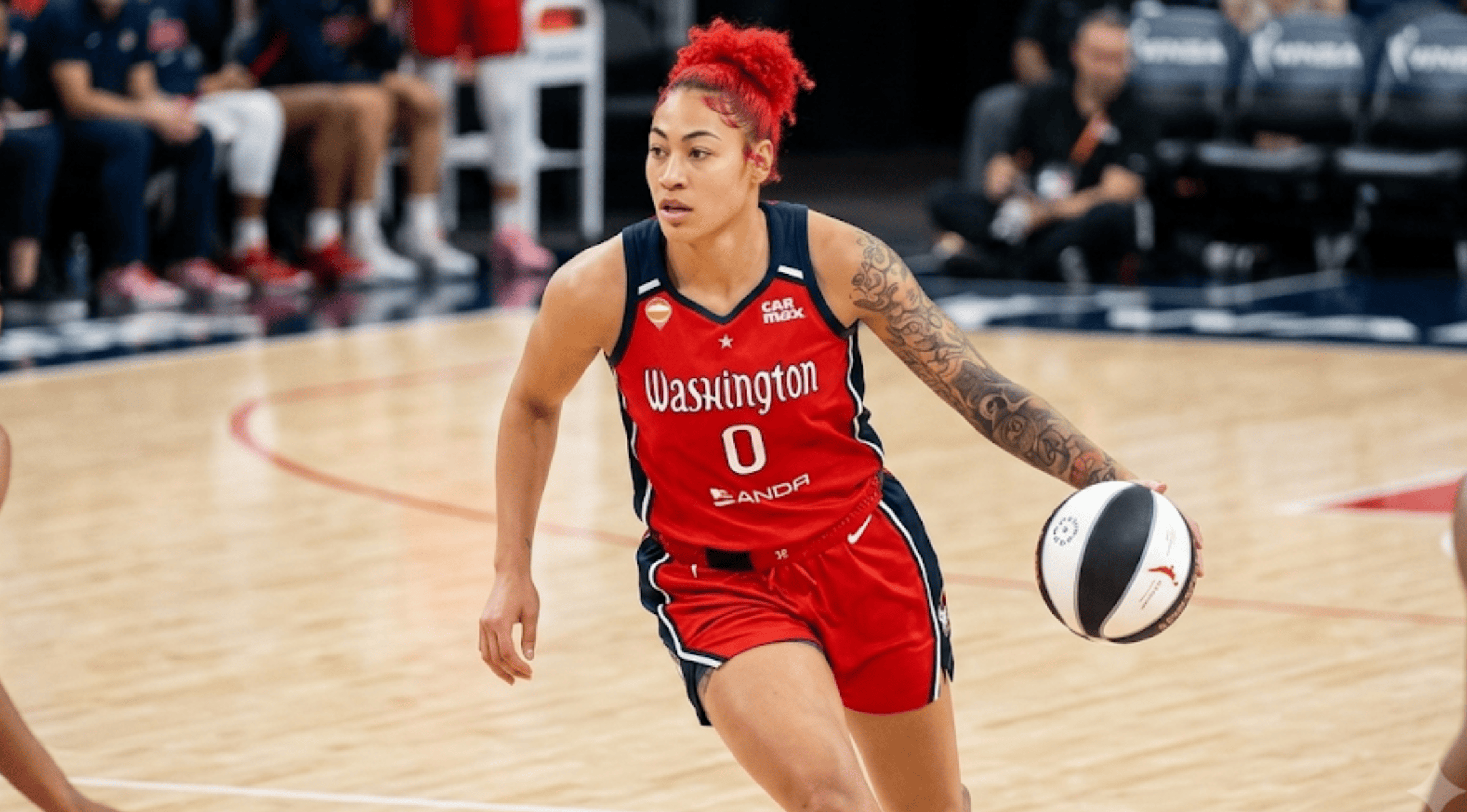 A close-up of the red Shakira Austin Washington Mystics jersey featuring a white gothic text layout, navy side panels, and player number 0.